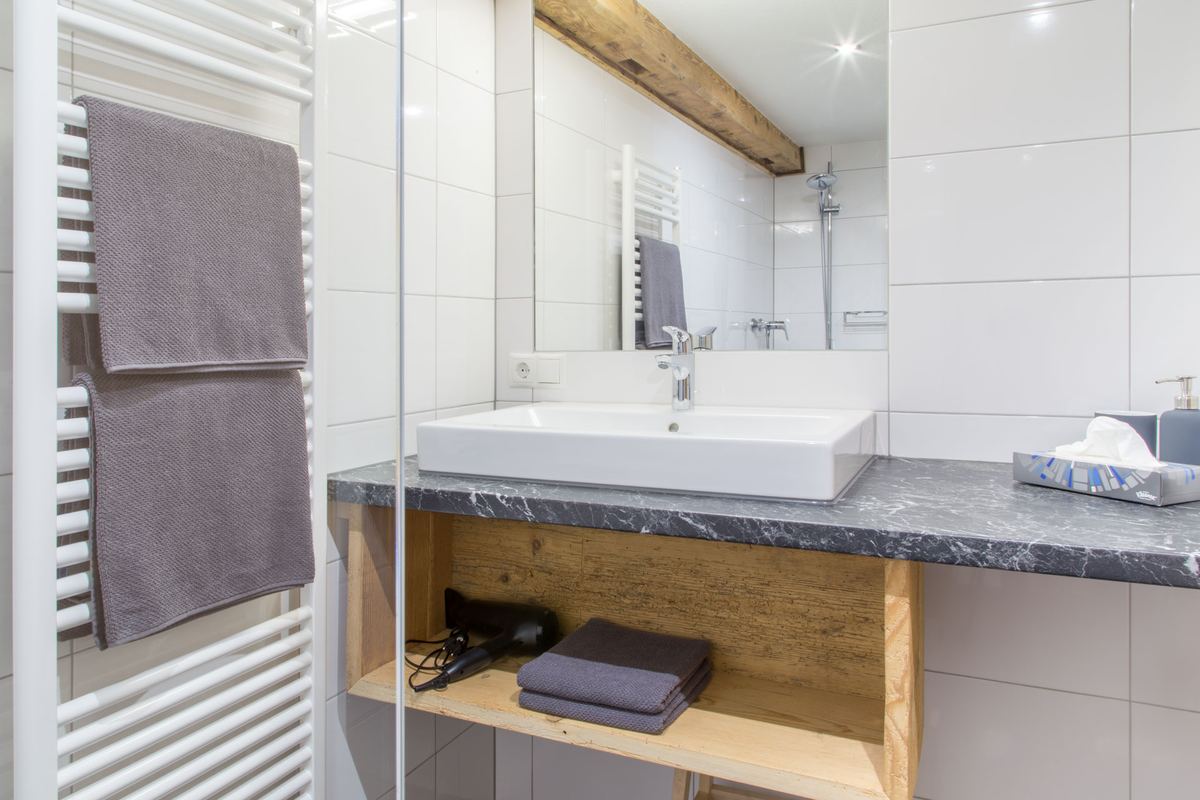 Badezimmer mit Waschtisch aus Stein, Spiegel und Handtuchheizkörper