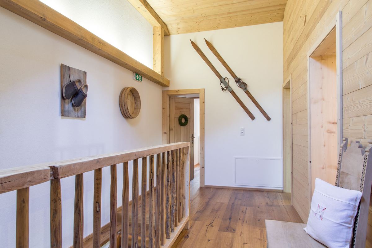 Hausflur mit Holzgeländer und alten Ski als Wandschmuck
