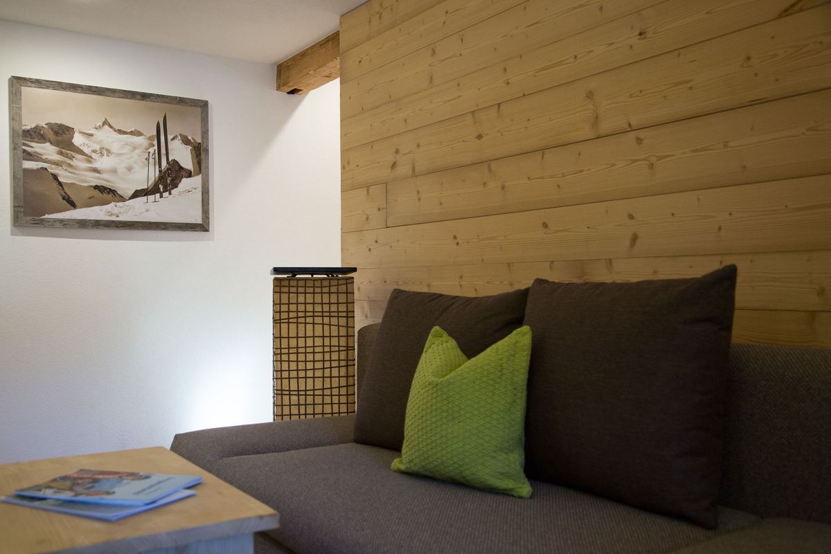 Leseecke mit Sofa, grünen Kissen und gerahmter Bergzeichnung