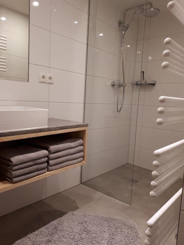Bad mit bodengleicher Dusche, Handtuchheizkörper und gestapelten Handtüchern