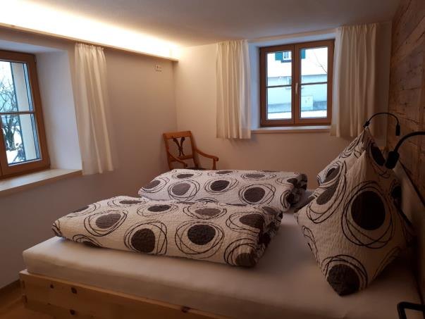 Schlafzimmer mit Doppelbett, gemusterter Bettwäsche und Fenster zum Tal