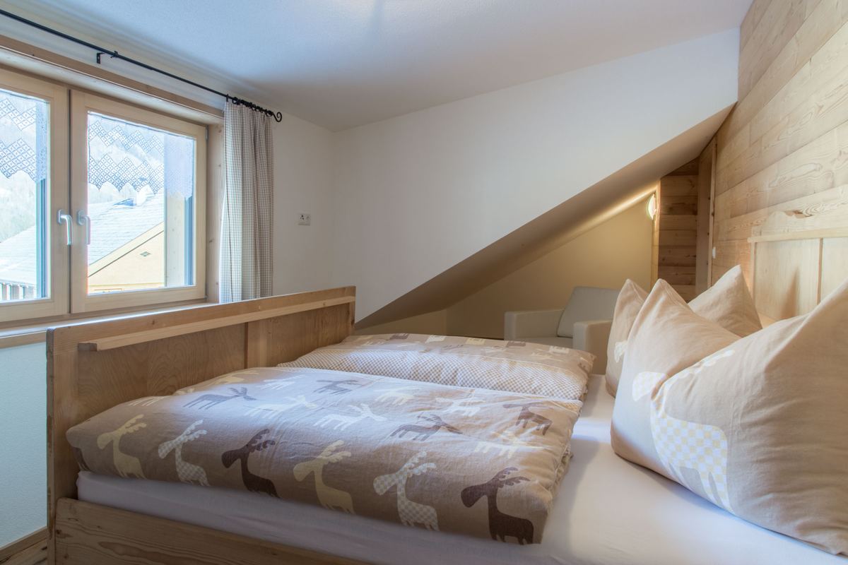 Schlafzimmer mit Doppelbett unter der Dachschräge und Fenster zum Tal