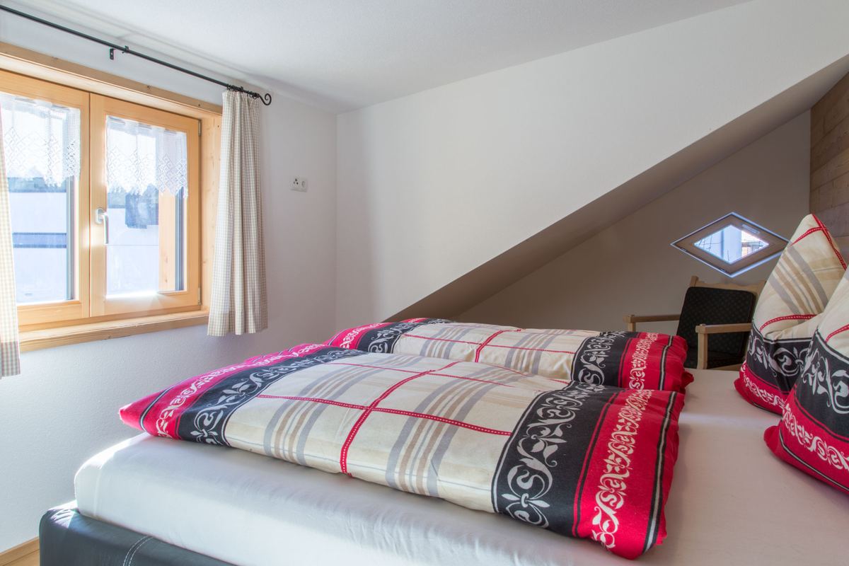 Schlafzimmer mit gemusterter Bettwäsche unter der Dachschräge