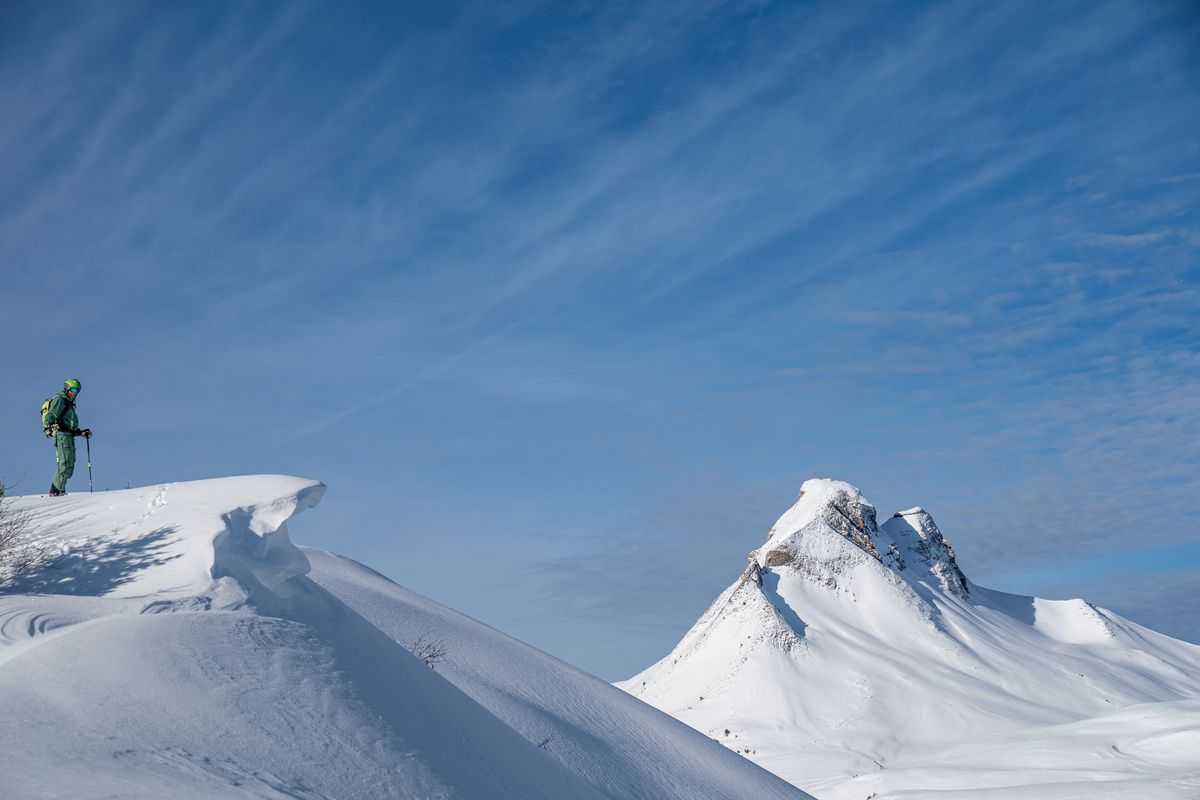Einzelner Skitourengeher auf einer Schneewächte vor tiefblauem Himmel im Skigebiet Damüls-Mellau