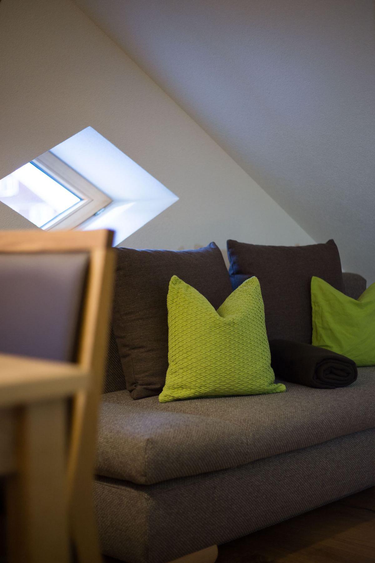 Sofa mit grünen Kissen unter dem Dachfenster